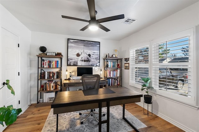 office area featuring light wood-style floors, visible vents, baseboards, and a ceiling fan