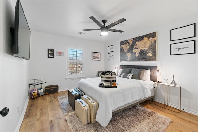 bedroom featuring ceiling fan, light wood-style flooring, visible vents, and baseboards