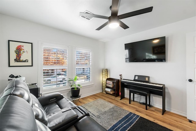 living area with light wood-style floors, ceiling fan, and baseboards