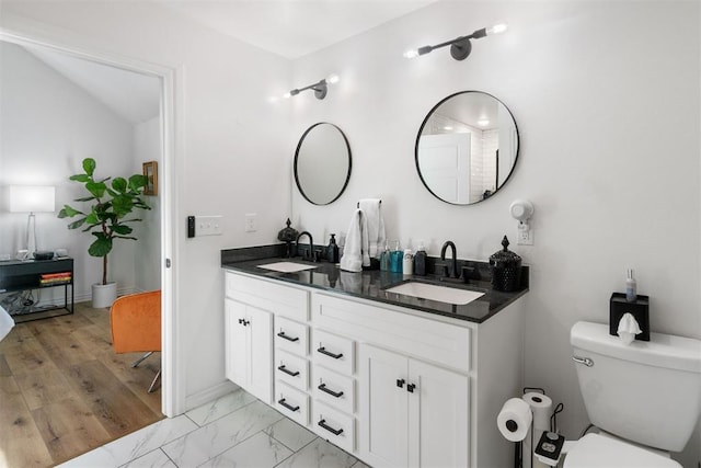 full bathroom with marble finish floor, a sink, toilet, and double vanity