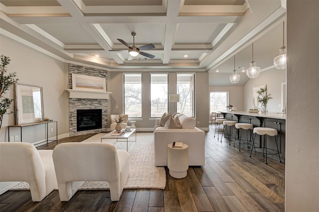 12709 Pinewood Ln, Oklahoma City, OK 73142 - living room featuring a stone fireplace, a ceiling fan, dark wood-type flooring, and beamed ceiling
