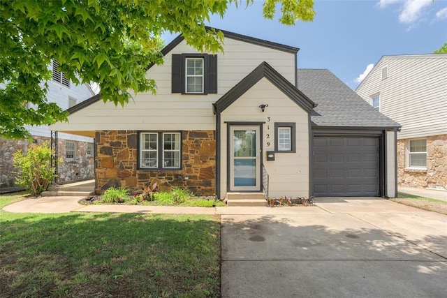 view of front of property with a shingled roof, concrete driveway, stone siding, an attached garage, and a front lawn