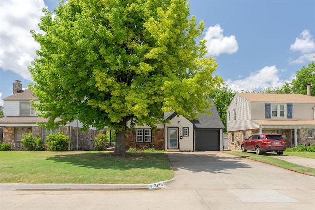 view of front of property featuring a garage, driveway, stone siding, and a front yard