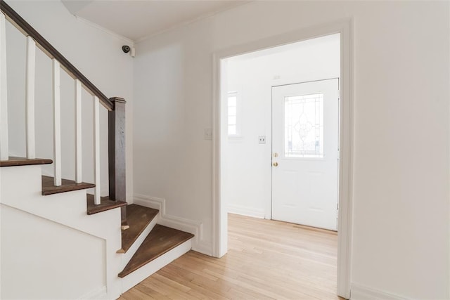 foyer with baseboards, stairway, and light wood-style floors