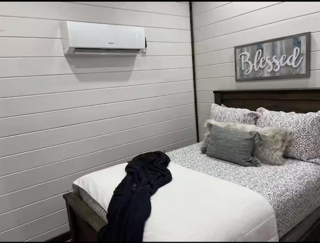 bedroom featuring a wall unit AC and wood walls