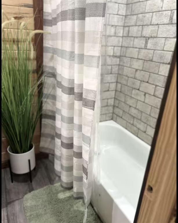 bathroom featuring shower / tub combo and wood finished floors