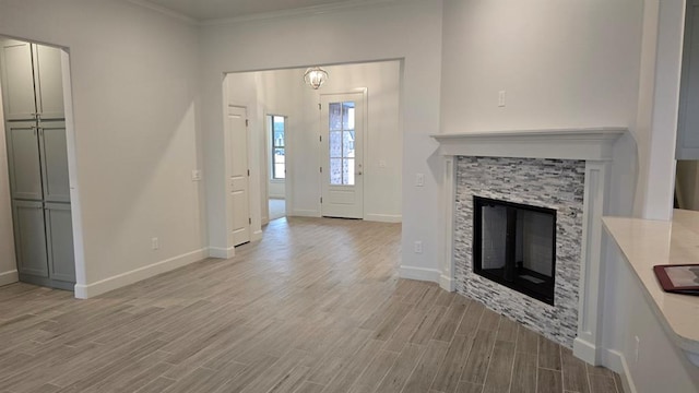 unfurnished living room with light wood finished floors, baseboards, a fireplace, and ornamental molding