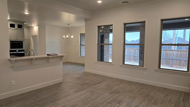 kitchen with baseboards, dark wood-style floors, ornamental molding, a chandelier, and a sink