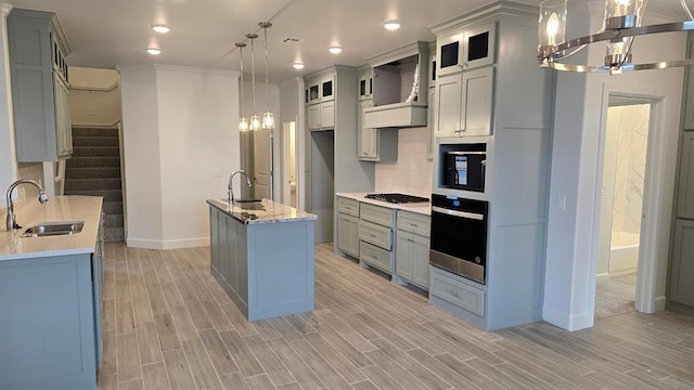 kitchen featuring tasteful backsplash, premium range hood, stainless steel appliances, and a sink