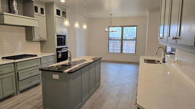 kitchen featuring gas stovetop, decorative backsplash, light wood-style floors, a sink, and premium range hood