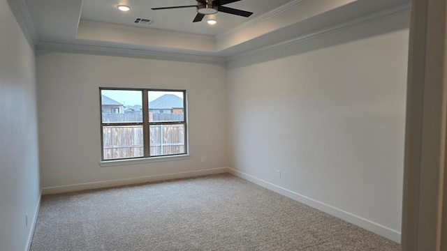 empty room featuring ornamental molding, a tray ceiling, visible vents, and baseboards