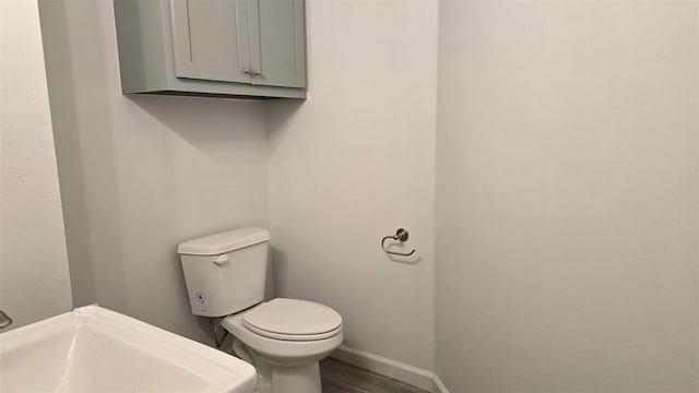 half bathroom with baseboards, a sink, and toilet