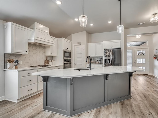 kitchen featuring stainless steel appliances, premium range hood, a sink, visible vents, and white cabinetry