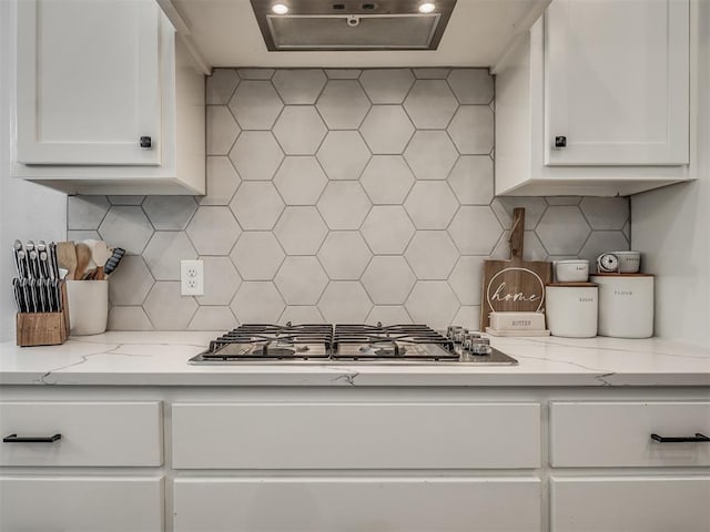 kitchen featuring light stone counters, white cabinets, ventilation hood, decorative backsplash, and stainless steel gas stovetop