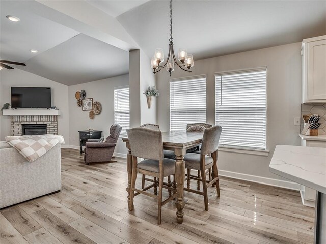 dining space with lofted ceiling, light wood finished floors, a fireplace, and baseboards