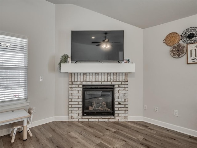 living room featuring a fireplace, ceiling fan, vaulted ceiling, wood finished floors, and baseboards