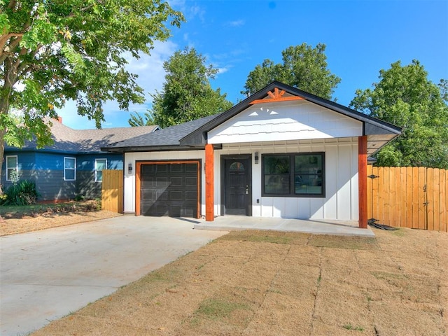 view of front of home with driveway, a shingled roof, an attached garage, fence, and board and batten siding