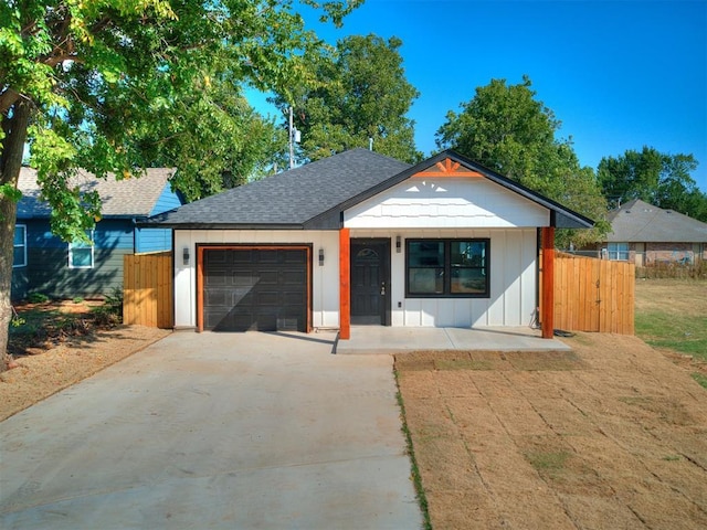 view of front of property with a garage, fence, driveway, roof with shingles, and board and batten siding