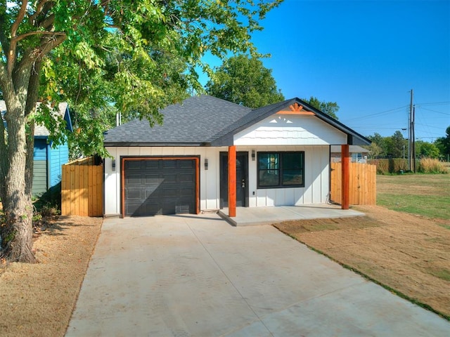 view of front of property with a garage, concrete driveway, a shingled roof, and fence