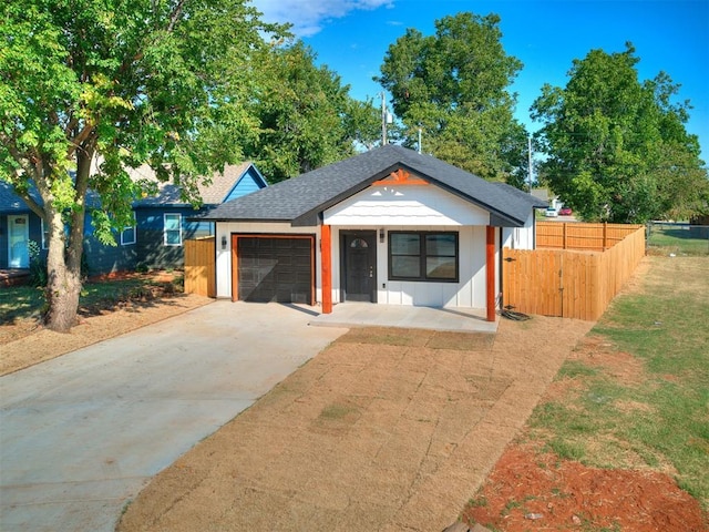 view of front of property featuring driveway, an attached garage, fence, and roof with shingles