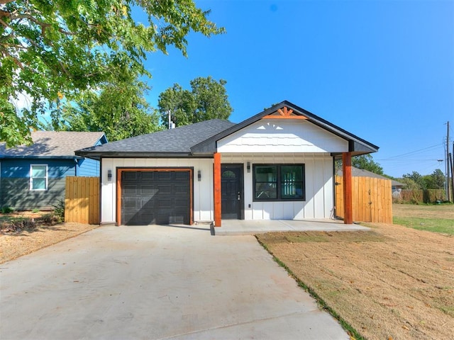 view of front facade featuring driveway, board and batten siding, an attached garage, and fence