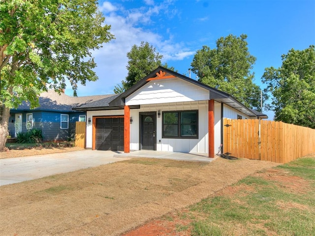 view of front of house featuring an attached garage, fence, and concrete driveway