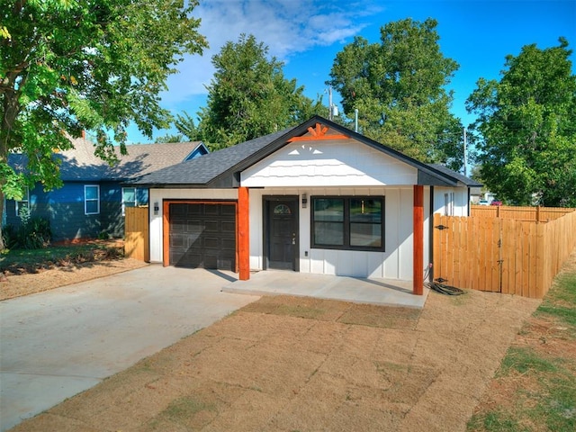 view of front of home featuring driveway, roof with shingles, an attached garage, and fence