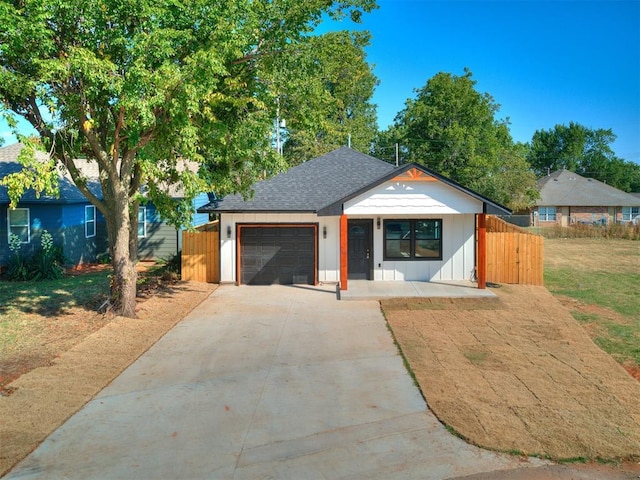 view of front of house with a garage, driveway, fence, and a shingled roof