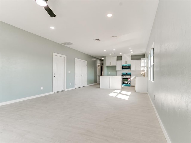 unfurnished living room with baseboards, visible vents, and a ceiling fan