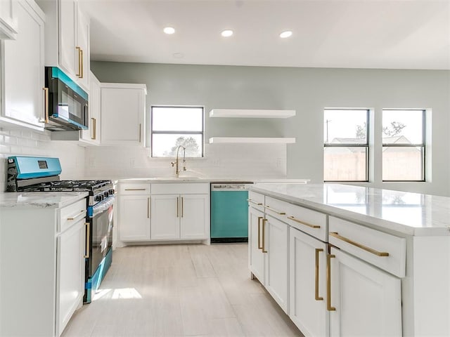 kitchen with tasteful backsplash, white cabinets, dishwasher, stainless steel gas range, and a sink