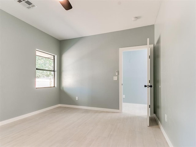 empty room featuring ceiling fan, light wood-style floors, visible vents, and baseboards