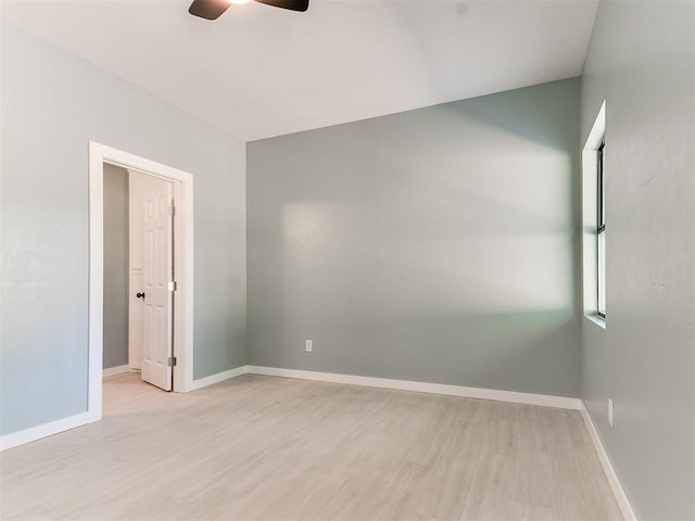 spare room featuring light wood-type flooring, a ceiling fan, and baseboards