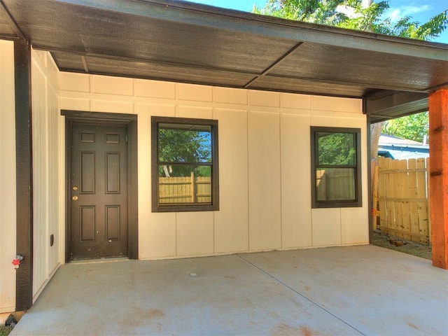 view of exterior entry with a patio area and fence