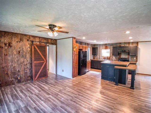 kitchen featuring a center island, a barn door, freestanding refrigerator, light wood-type flooring, and under cabinet range hood