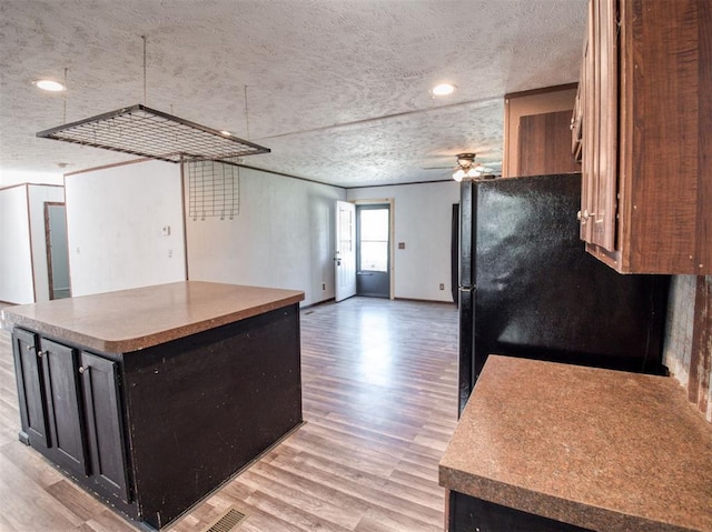 kitchen with a center island, light wood-style floors, freestanding refrigerator, open floor plan, and a textured ceiling