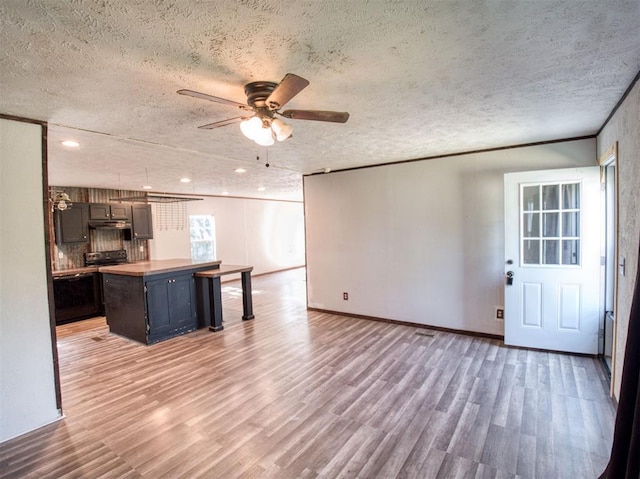 kitchen with a ceiling fan, light countertops, a textured ceiling, light wood-type flooring, and range with electric stovetop