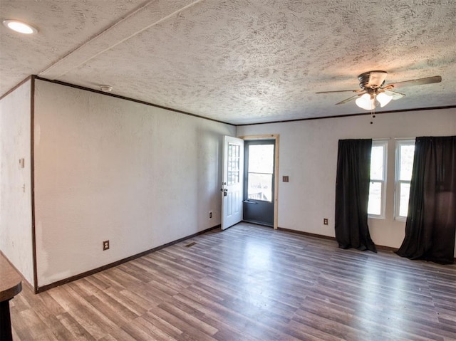 unfurnished room featuring ornamental molding, wood finished floors, a wealth of natural light, and baseboards