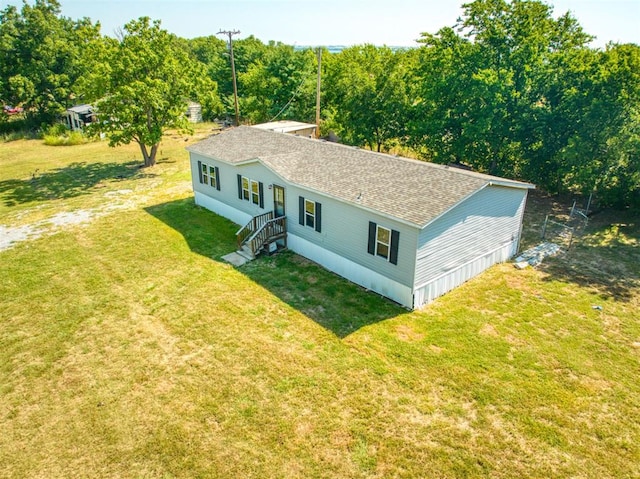 exterior space featuring roof with shingles and a front yard