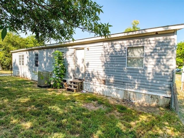 view of side of property featuring entry steps, a yard, and central air condition unit