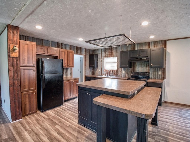 kitchen featuring a kitchen island, light wood-type flooring, a sink, and black appliances