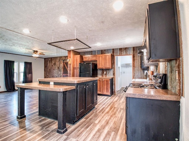 kitchen with light wood-style flooring, a kitchen island, freestanding refrigerator, stainless steel electric stove, and a textured ceiling