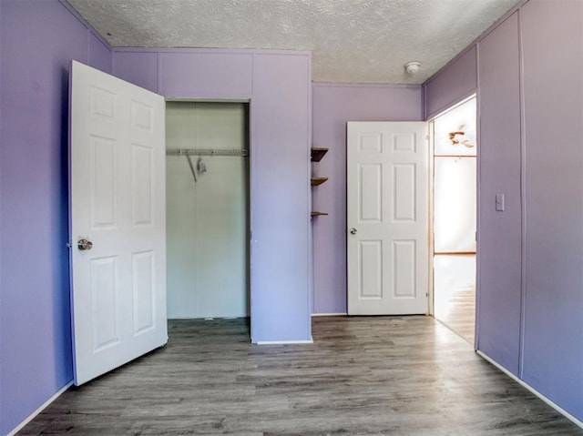 unfurnished bedroom featuring a textured ceiling, a closet, and wood finished floors