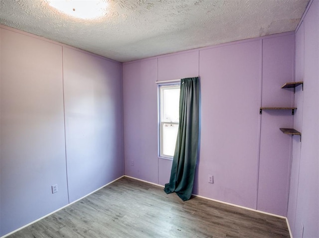 spare room featuring a textured ceiling and wood finished floors