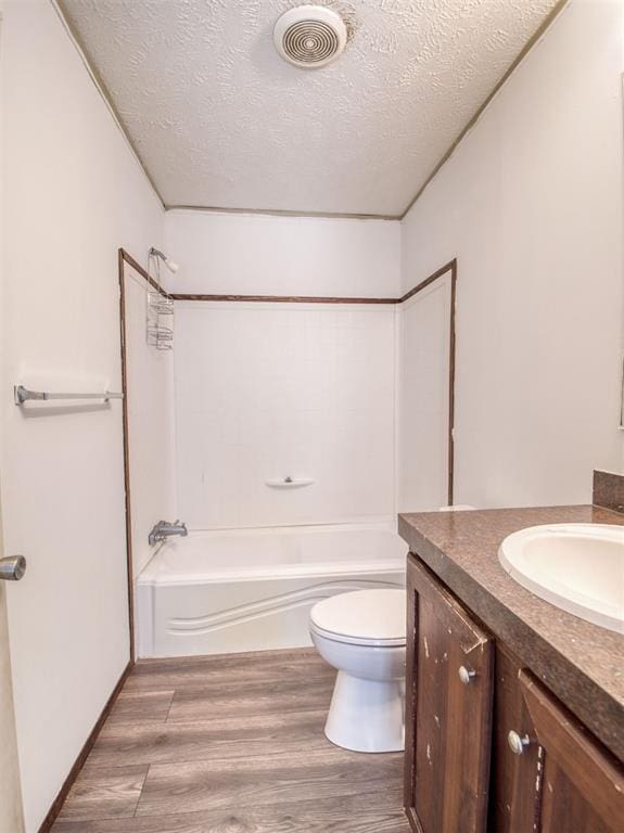 bathroom featuring a textured ceiling, toilet, wood finished floors, vanity, and visible vents