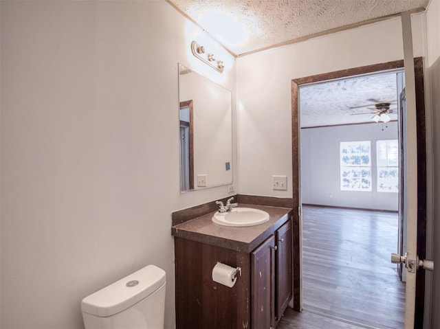 bathroom featuring a ceiling fan, toilet, wood finished floors, a textured ceiling, and vanity