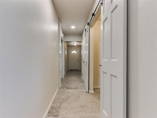 hallway with a barn door and baseboards