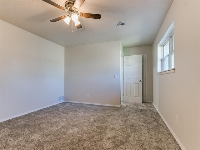 carpeted spare room featuring a ceiling fan, visible vents, and baseboards