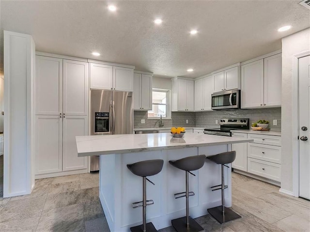 4329 NW 44th St, Oklahoma City, OK 73112 - kitchen with tasteful backsplash, a kitchen island, a breakfast bar area, appliances with stainless steel finishes, and a sink