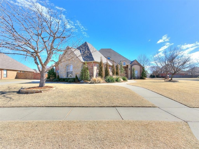 french country inspired facade with brick siding and a front lawn