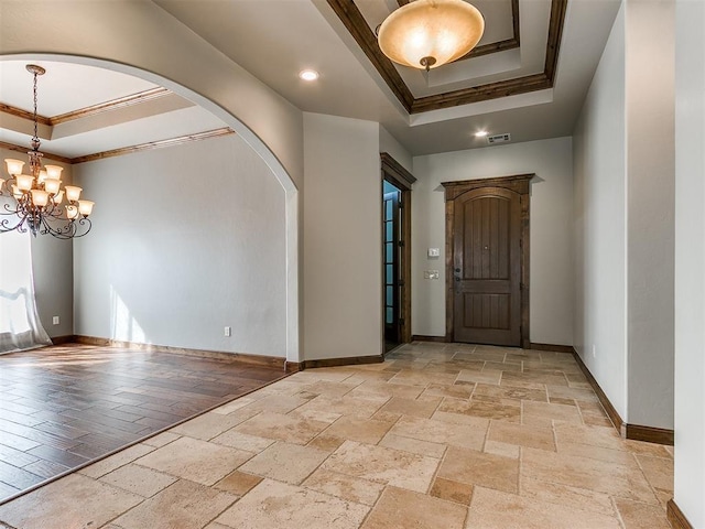 entrance foyer with a notable chandelier, baseboards, a raised ceiling, stone tile flooring, and crown molding